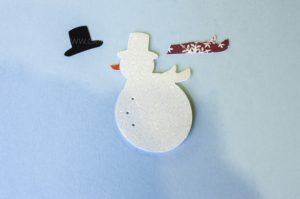 Use paper crafts to create a winter wonderland picture display for your home. Use a snowman hole punch and other paper craft items to create the scene.