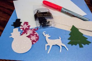 Use paper crafts to create a winter wonderland picture display for your home. Use a snowman hole punch and other paper craft items to create the scene.