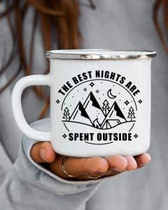 Circle with the words the best nights are spent outside around the outside of it. And on the inside there are mountains, trees, a tent and a fire