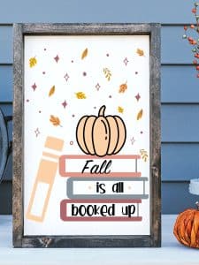 Fall leaves falling down around a stack of books with an orange pumpkin sitting on top of the books. On the bottom of the books there are words that read "Fall is all booked up"